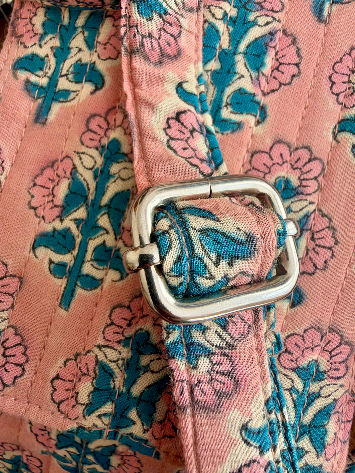 House of Mulmul - Blockprinted Mobile Sling Bag. Close-up of a pink mobile sling bag strap with a blue and cream pattern, featuring a silver metal buckle adjuster.