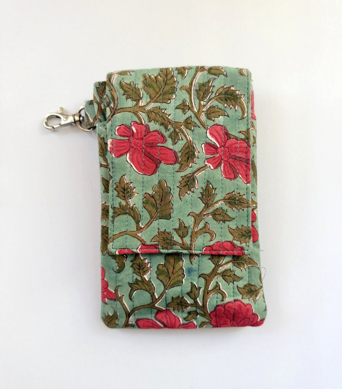 House of Mulmul - Blockprinted Mobile Sling Bag. A small fabric phone holder or wallet with a floral print, featuring red flowers and brown leaves on a light green background, with a silver metal clasp on the left side.