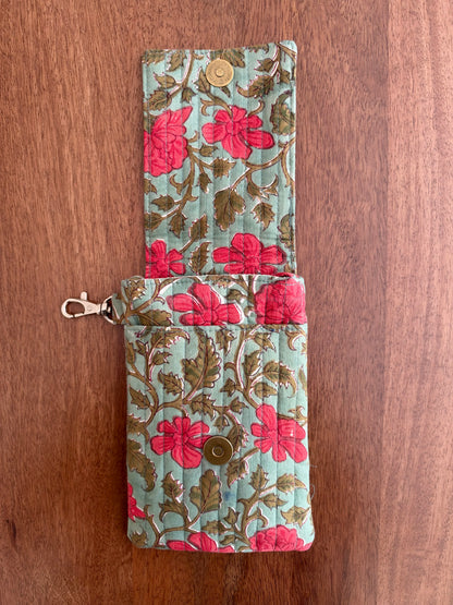 House of Mulmul - Blockprinted Mobile Sling Bag. A quilted fabric wallet with a floral print in pink and brown on a light blue-green background, shown open on a wooden surface.