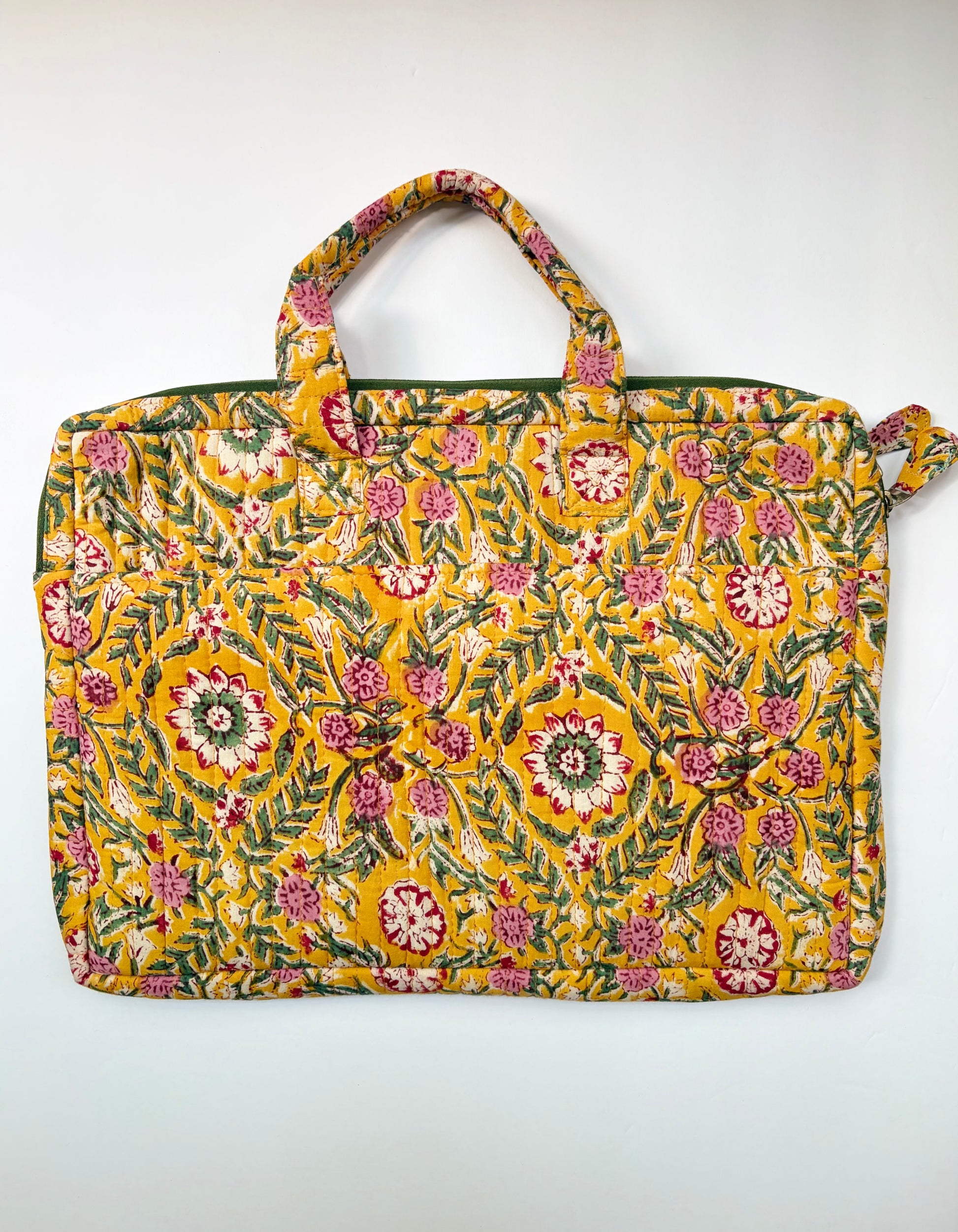 House of Mulmul - Blockprinted Cotton Quilted Laptop Bag. A rectangular fabric tote laptop bag with a vibrant yellow background and an all-over floral and botanical print in pink, green, and white. The bag features two top handles and a zipper closure at the top, photographed flat against a plain white background.