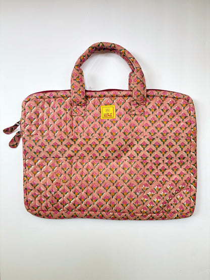 House of Mulmul - Blockprinted Cotton Quilted Laptop Bag. A quilted pink laptop sleeve featuring a repeating floral pattern in shades of pink, green, and yellow, with dual top handles and a small yellow brand tag on the front.