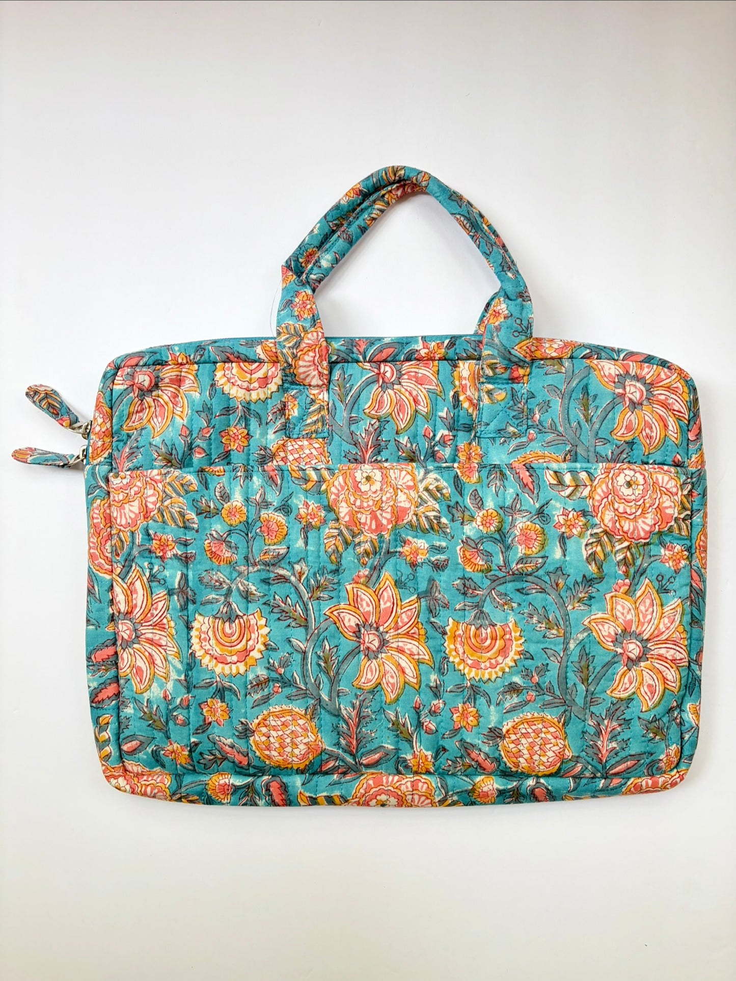 House of Mulmul - Blockprinted Cotton Quilted Laptop Bag. A quilted fabric laptop sleeve featuring a vibrant floral pattern in teal, orange, and yellow, with dual top handles and zippered side pockets, shown against a plain off-white background.
