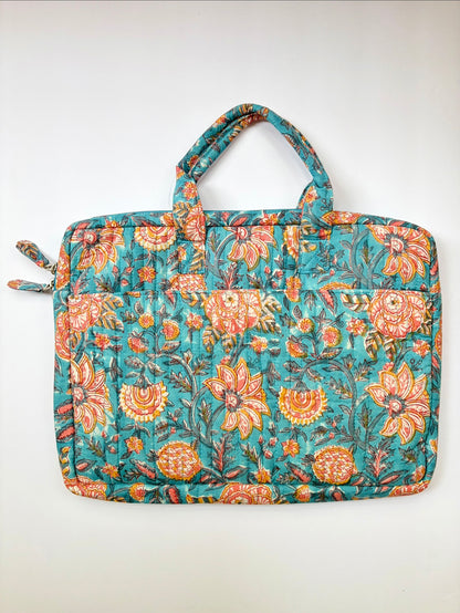 House of Mulmul - Blockprinted Cotton Quilted Laptop Bag. A quilted fabric laptop sleeve featuring a vibrant floral pattern in teal, orange, and yellow, with dual top handles and zippered side pockets, shown against a plain off-white background.