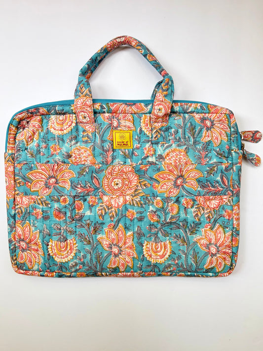 House of Mulmul - Blockprinted Cotton Quilted Laptop Bag. A quilted laptop sleeve featuring a vibrant floral pattern in teal, orange, and pink, with a small yellow brand patch on the front.