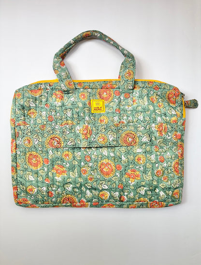 House of Mulmul - Blockprinted Cotton Quilted Laptop Bag. A quilted fabric tote  laptop bag featuring a green base with a dense orange, red, and white floral pattern, complete with two top handles and a small yellow brand label on the front.