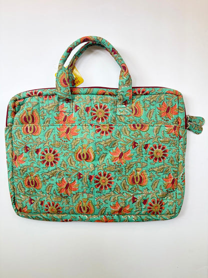 House of Mulmul - Blockprinted Cotton Quilted Laptop Bag. A quilted laptop bag with a vibrant turquoise green background and an all-over floral and paisley block-print pattern in orange, red, and gold, featuring dual top handles and a side strap.