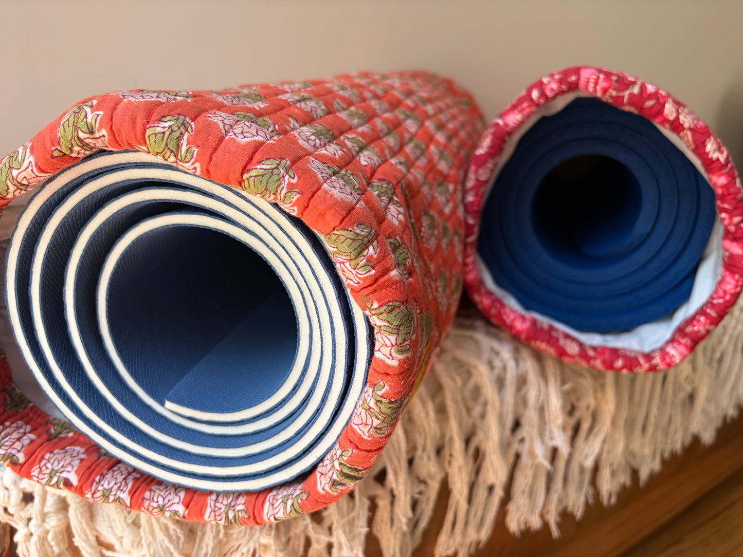 House of Mulmul - Blockprinted Yoga Mat Cover. Two rolled-up yoga mats with floral patterns on a wooden surface.