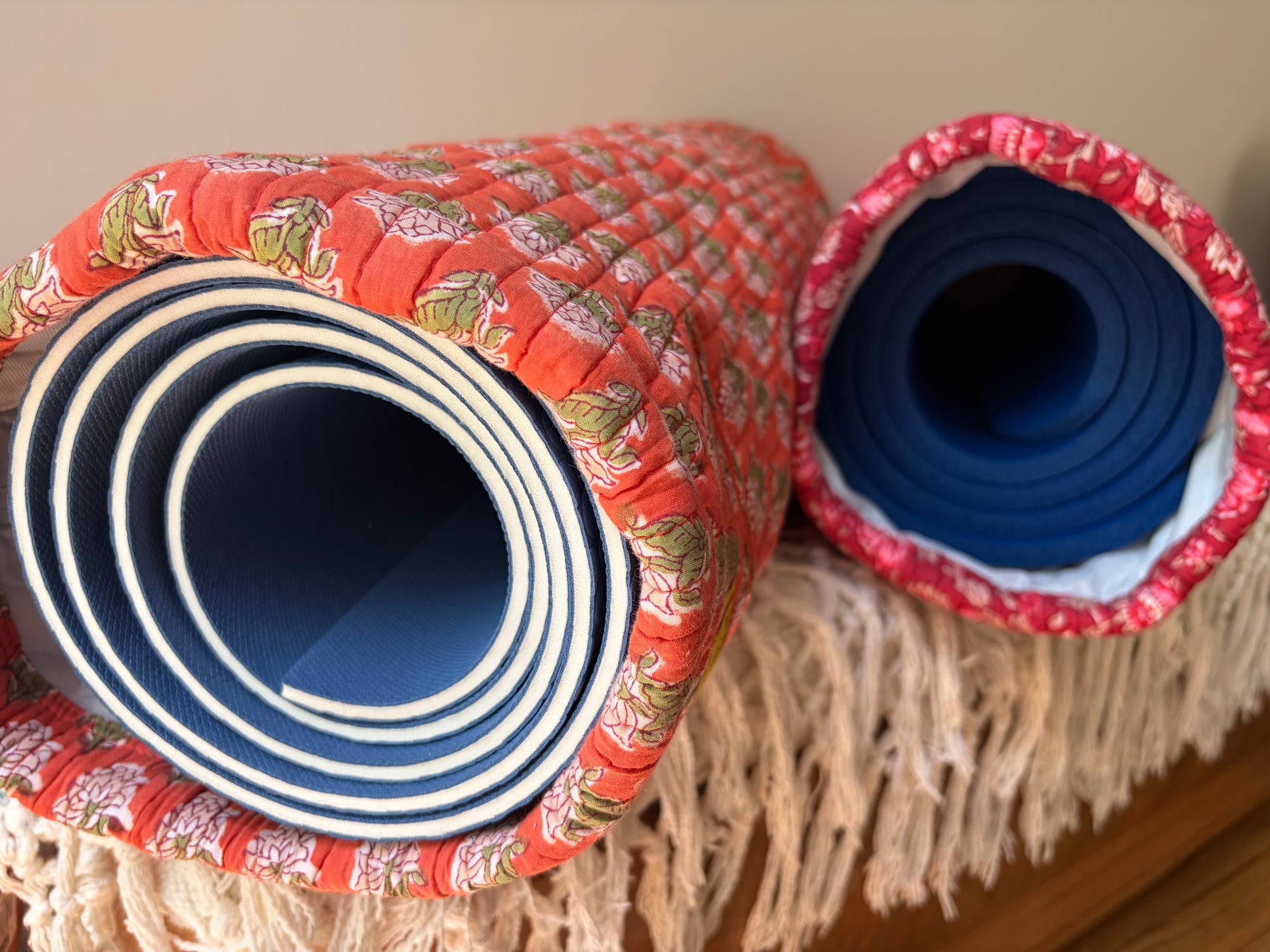 House of Mulmul - Blockprinted Yoga Mat Cover. Two rolled-up yoga mats with floral patterns on a wooden surface.