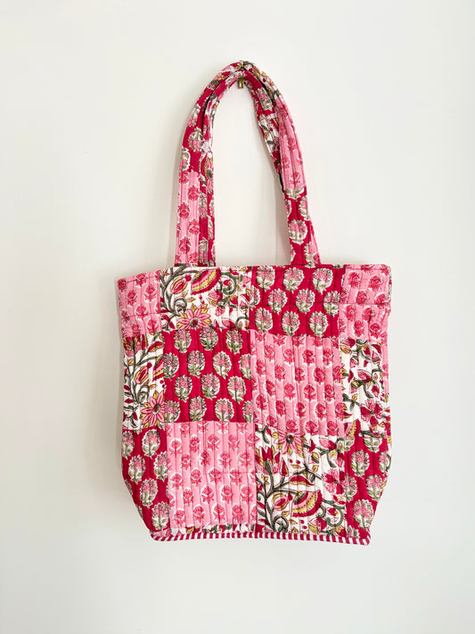 House of Mulmul - Bucket Tapered Tote Bag. A pink patchwork quilted tote bag with floral and geometric prints, featuring two top handles, shown against a plain white background.