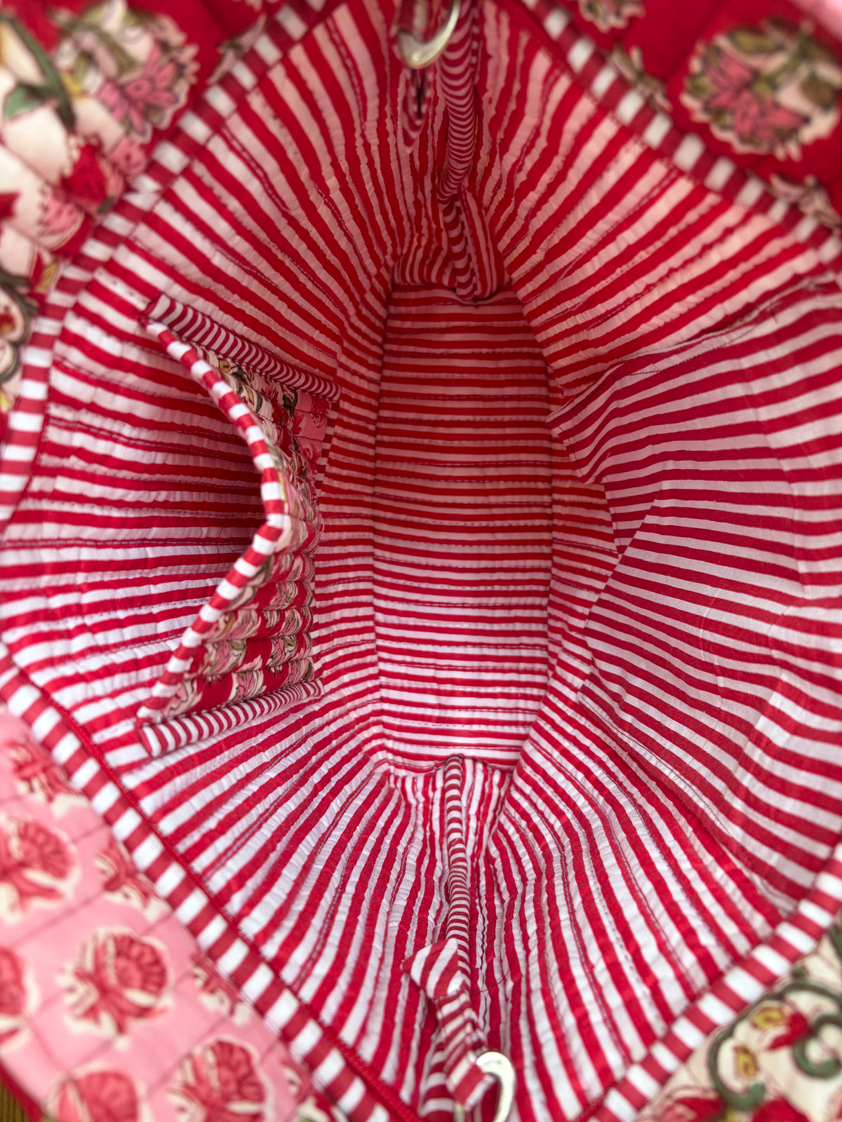 House of Mulmul - Bucket Tapered Tote Bag. Close-up of a red and white striped fabric interior with a floral patterned pocket and matching red and white striped lining.