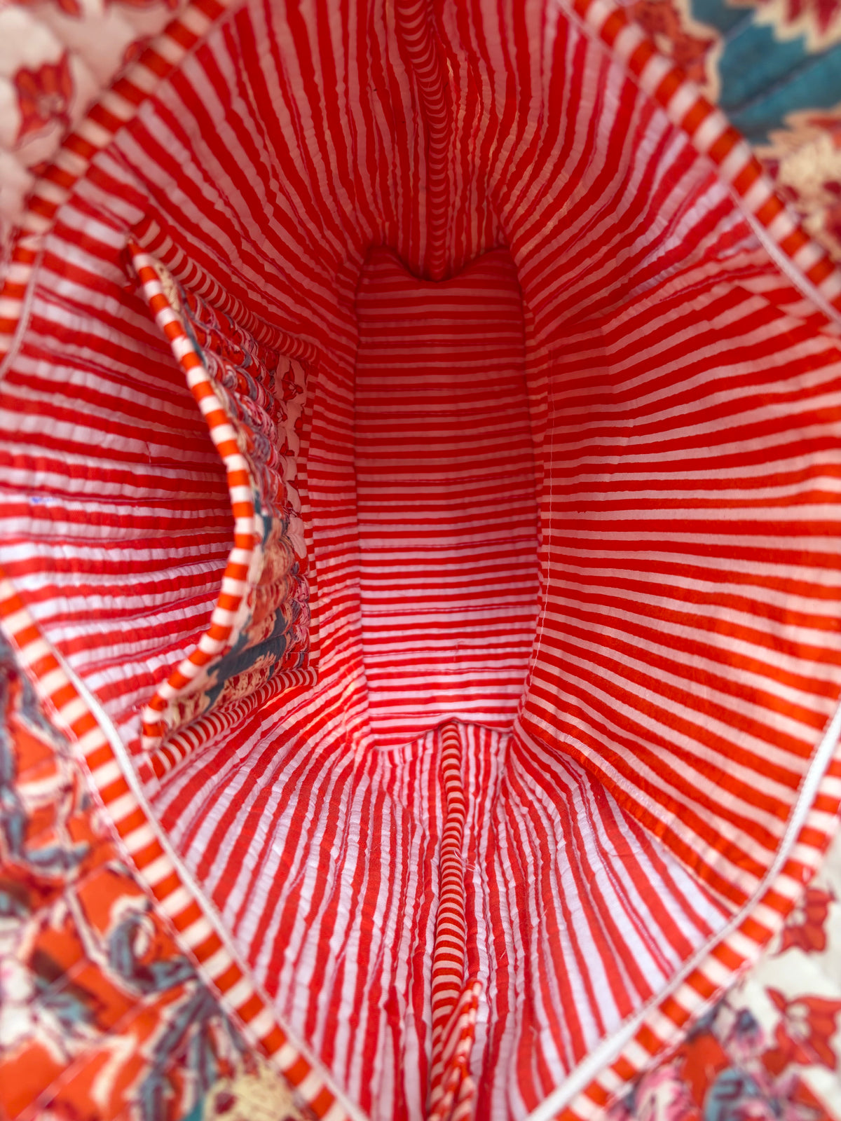House of Mulmul - Bucket Tapered Tote Bag. Close-up of the interior lining of a fabric bag or pouch, featuring a red and white striped pattern with a small side pocket on the left.