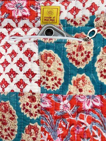 House of Mulmul - Bucket Tapered Tote Bag. Close-up of a quilted patchwork fabric item with floral and paisley patterns in red, teal, cream, and pink, featuring a silver zipper and a yellow 'HOUSE OF MULMUL' brand label.