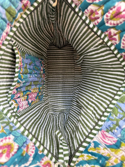 House of Mulmul - Bucket Tapered Tote Bag. Close-up of the interior of a quilted fabric bag or basket, showing a striped green and white fabric lining with a colorful floral patterned fabric attached on the left side.
