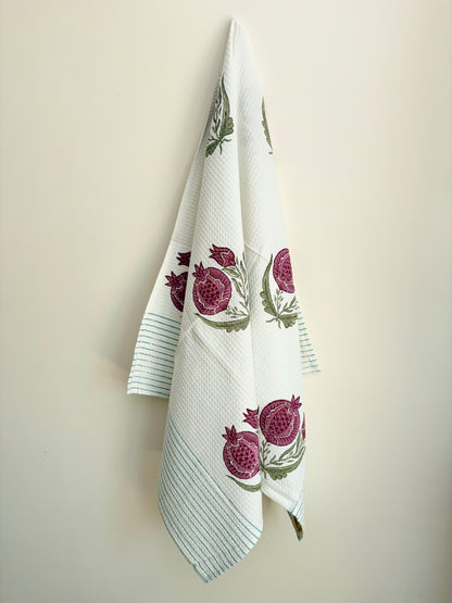 House of Mulmul - Cotton Bath Towel. White towel with pomegranate designs hanging on a beige wall