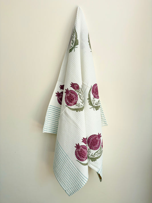 House of Mulmul - Cotton Bath Towel. White towel with pomegranate designs hanging on a beige wall