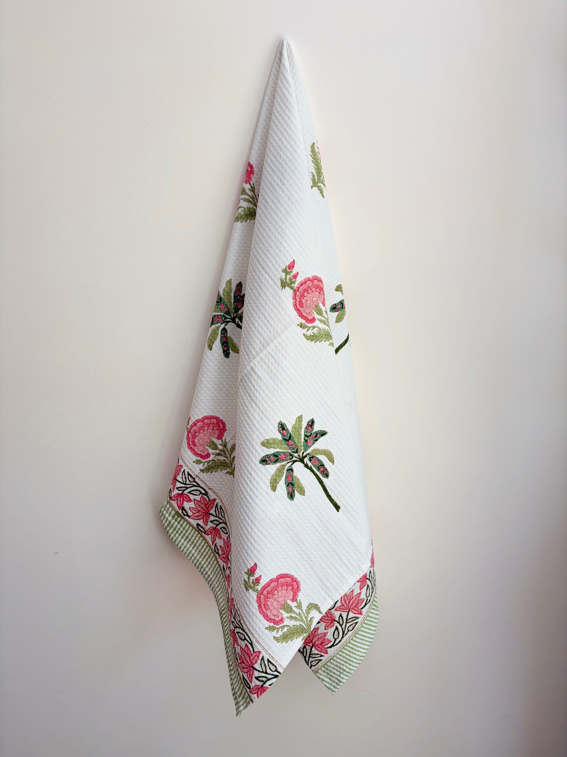 House of Mulmul - Cotton Bath and Hand Towel set. Floral patterned towel hanging on a white wall