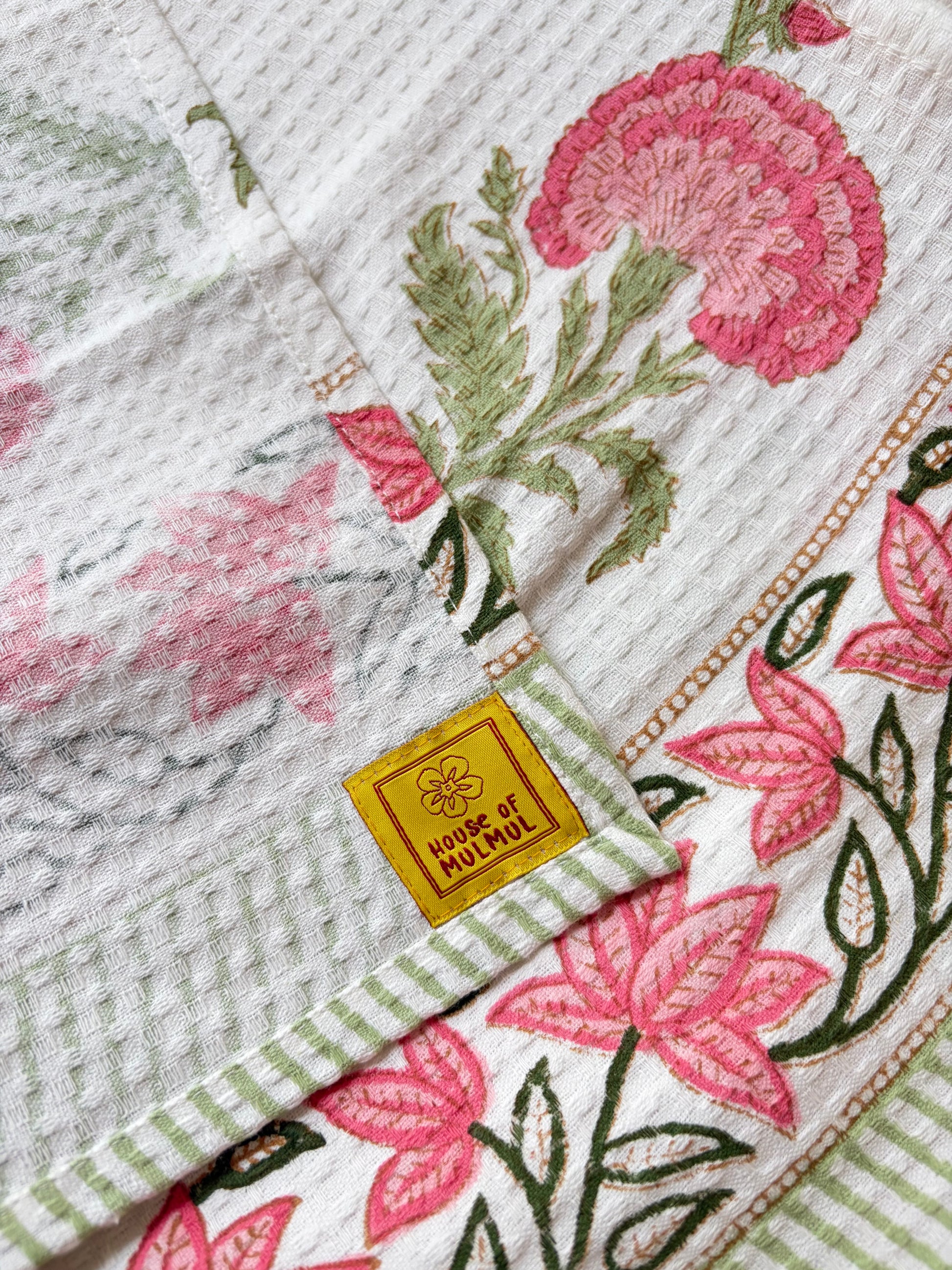 House of Mulmul - Cotton Bath and Hand Towel set. Close-up of cotton towel with floral patterns on a beige background