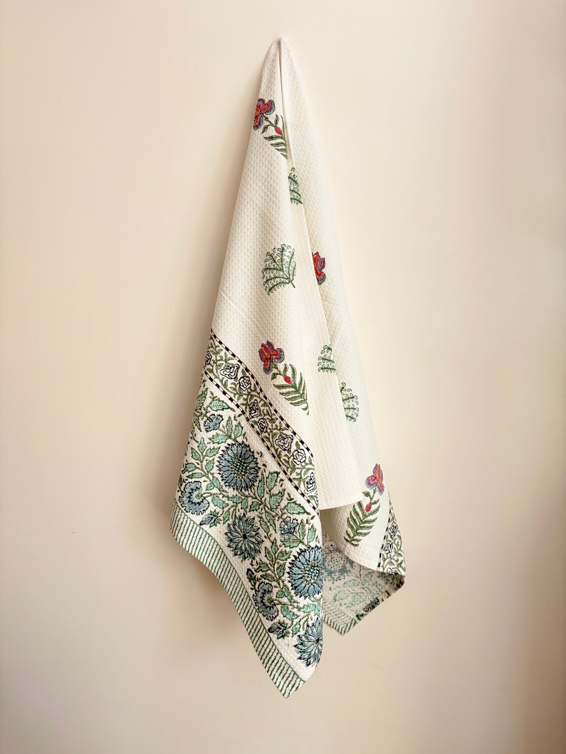 House of Mulmul - Cotton Bath Towel. Floral patterned towel hanging on a beige wall
