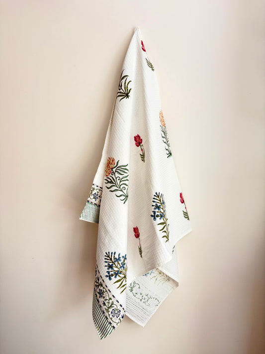 House of Mulmul - Cotton Bath Towel. Decorative cotton towel with floral patterns hanging on a beige wall
