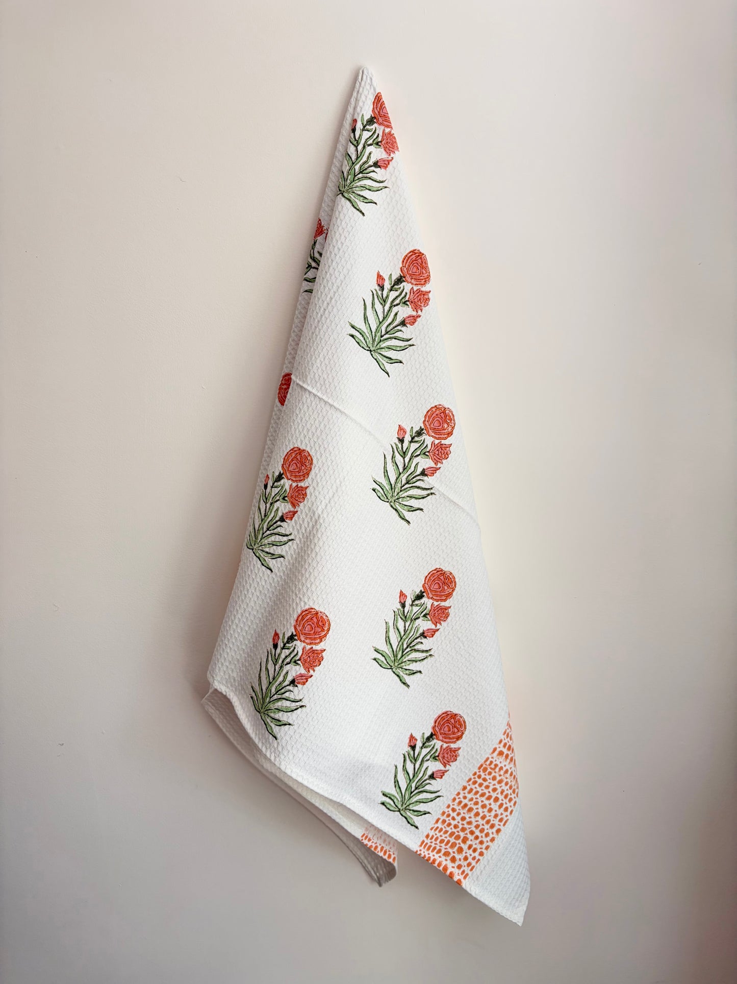 House of Mulmul - Cotton Bath and Hand Towel set. Floral patterned towel hanging on a white wall