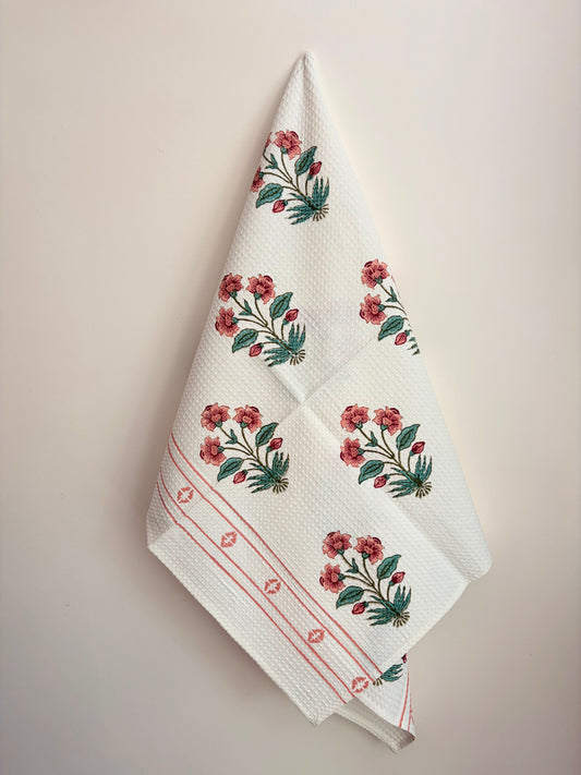 House of Mulmul - Cotton Bath Towel. Floral patterned towel hanging against a plain background