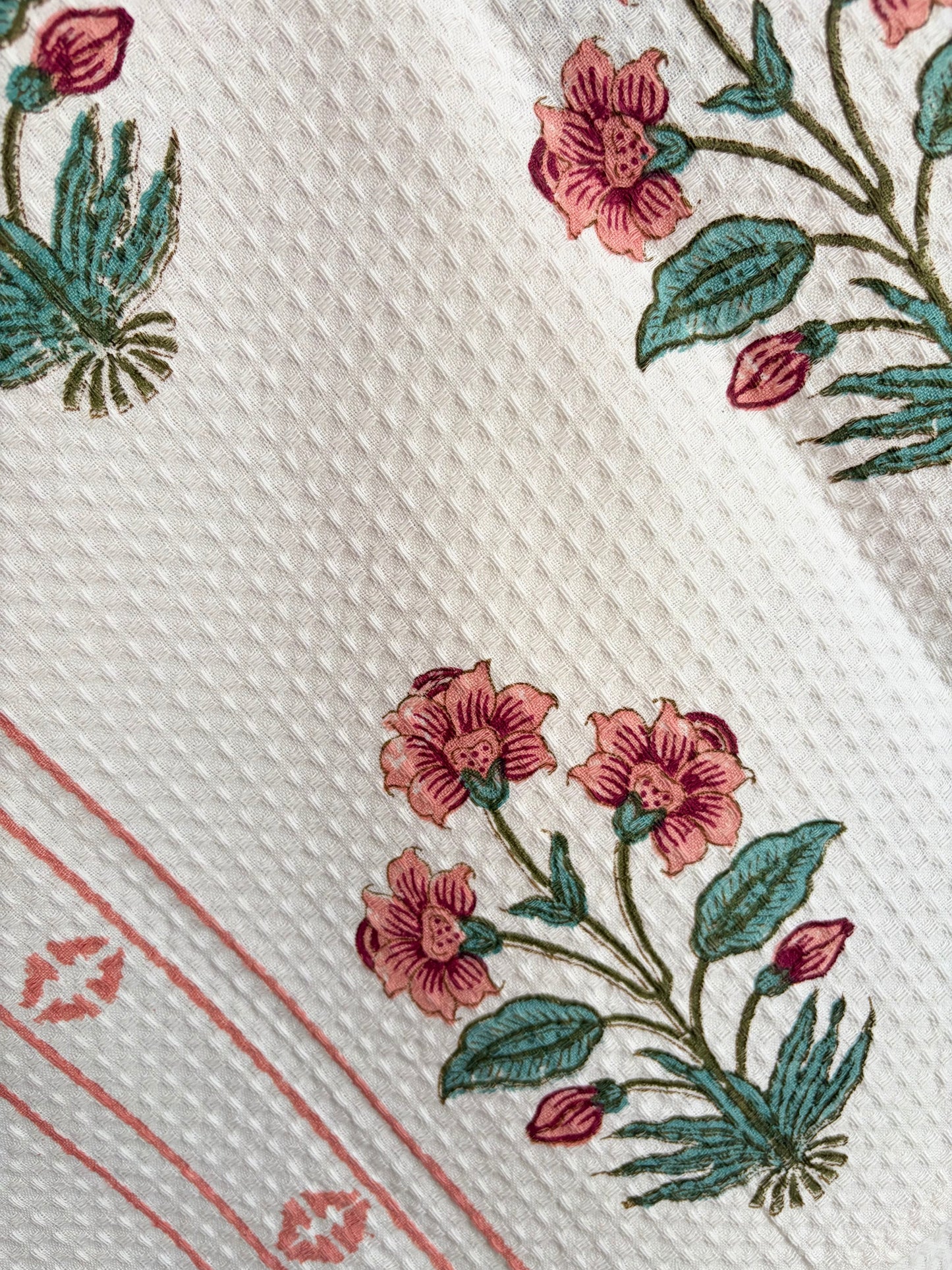 House of Mulmul - Cotton Bath Towel. Close-up of a cotton towel with floral patterns and red lines on a white background