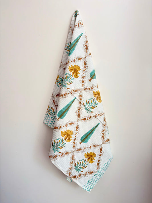 House of Mulmul - Cotton Bath Towel. Floral patterned towel hanging against a plain background