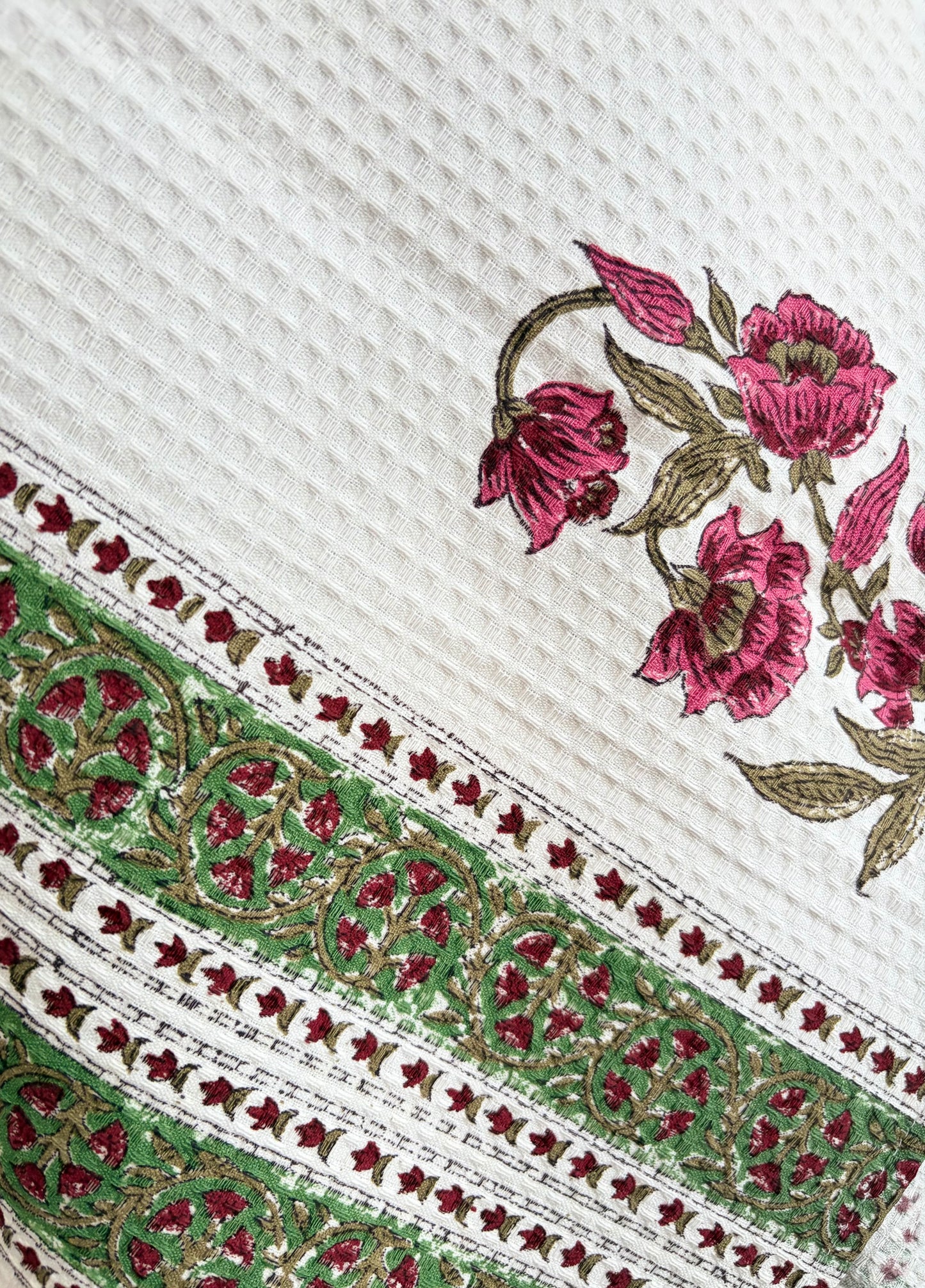 House of Mulmul - Cotton Bath Towel. Close-up of embroidered towel with floral patterns on a white background