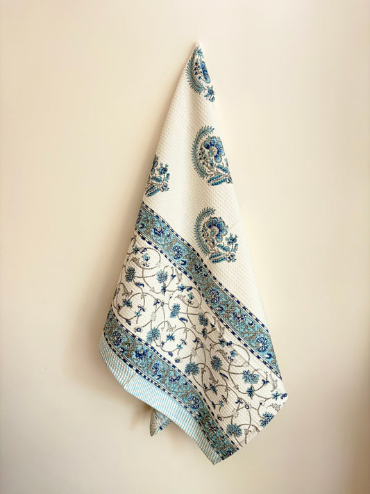 House of Mulmul - Cotton Bath Towel. Decorative towel with blue floral patterns hanging on a beige wall