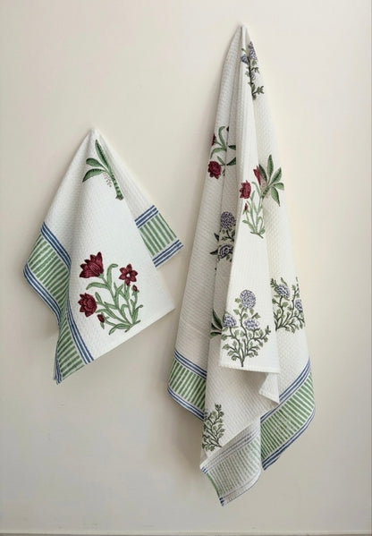 House of Mulmul - Cotton Bath and Hand Towel set. Two decorative towels with floral patterns hanging on a wall.