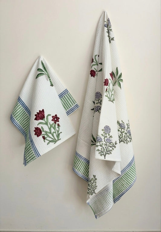 House of Mulmul - Cotton Bath and Hand Towel set. Two decorative towels with floral patterns hanging on a wall.