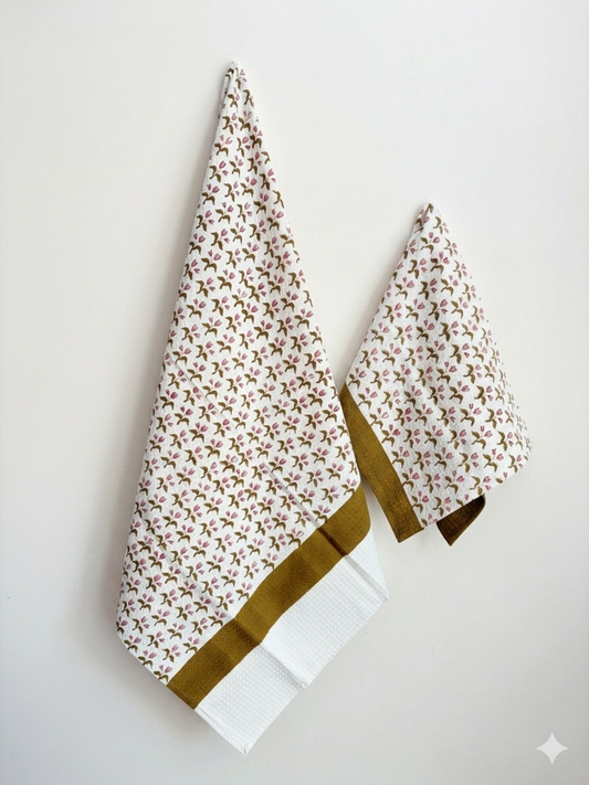 House of Mulmul - Cotton Bath and Hand Towel set. Two floral-patterned towels with a gold border on a light gray background