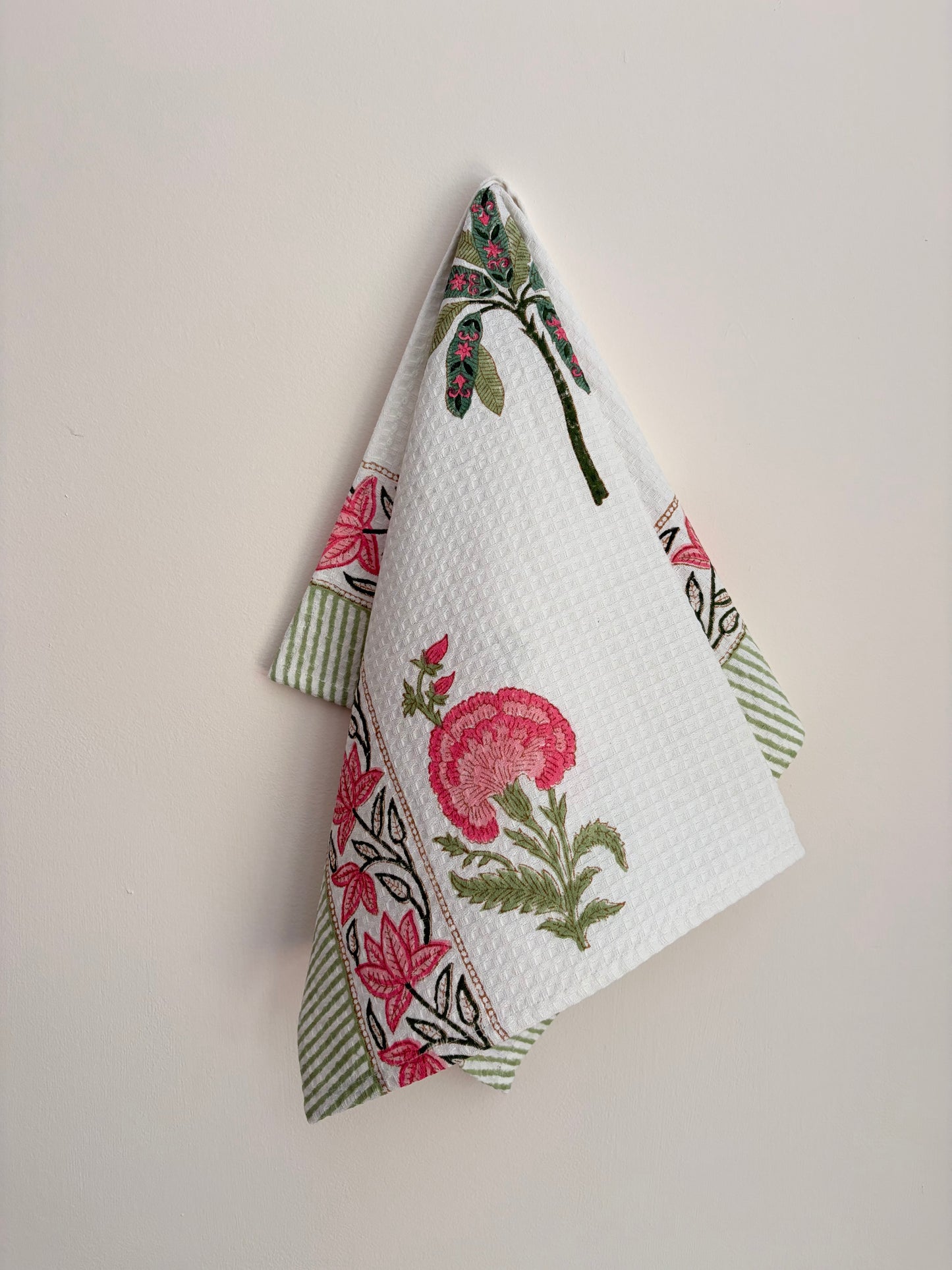 House of Mulmul - Cotton Bath and Hand Towel set. Floral patterned towel hanging on a hook against a plain background