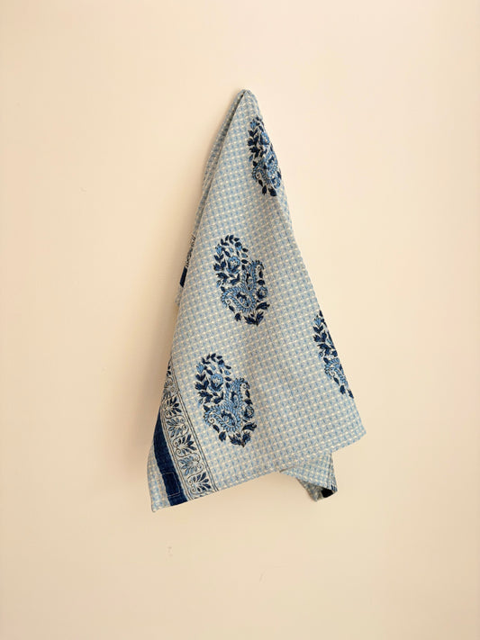 House of Mulmul - Cotton Hand Towel. Blue patterned towel hanging on a beige wall