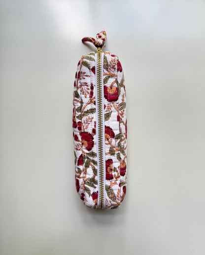House of Mulmul - Cotton Quilted Makeup Barrel Pouch. A vertical zippered pouch with a white background and a red, green, and brown floral pattern, featuring a small matching fabric loop at the top and a gold zipper.