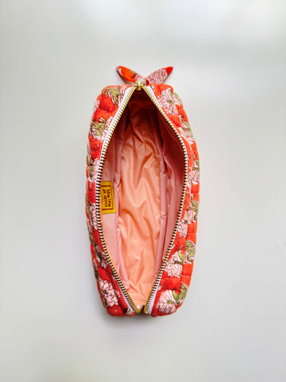 House of Mulmul - Cotton Quilted Makeup Barrel Pouch. An open quilted cosmetic pouch with a red and orange floral patterned exterior, a peach-pink satin interior, and a small yellow tag on a white background.