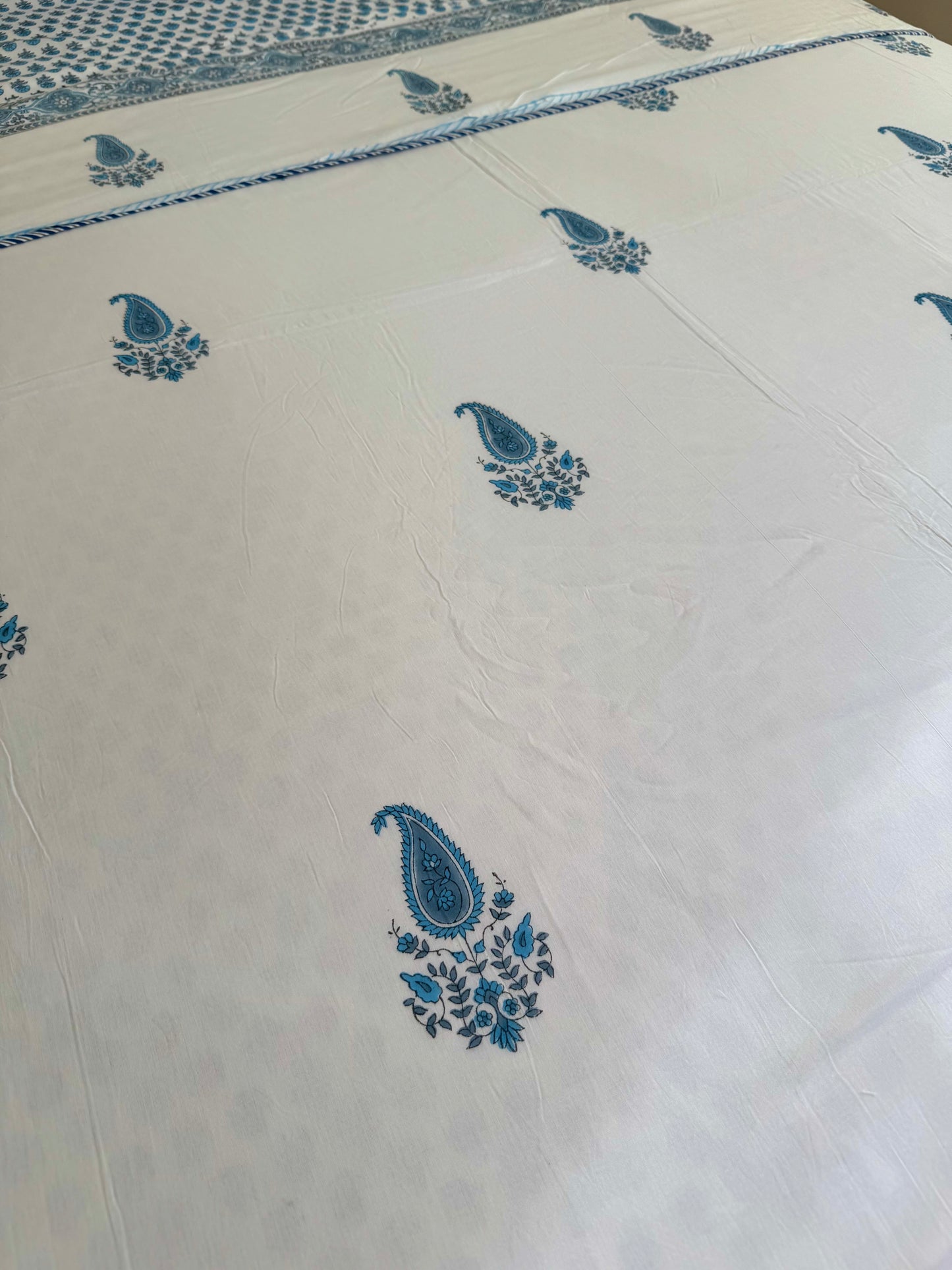 House of Mulmul - Coverlet Dohar blanket. Bedroom with reversible cotton coverlet blanket. Muslin dohar with boota paisley leaf and blue and grey colors, white background.