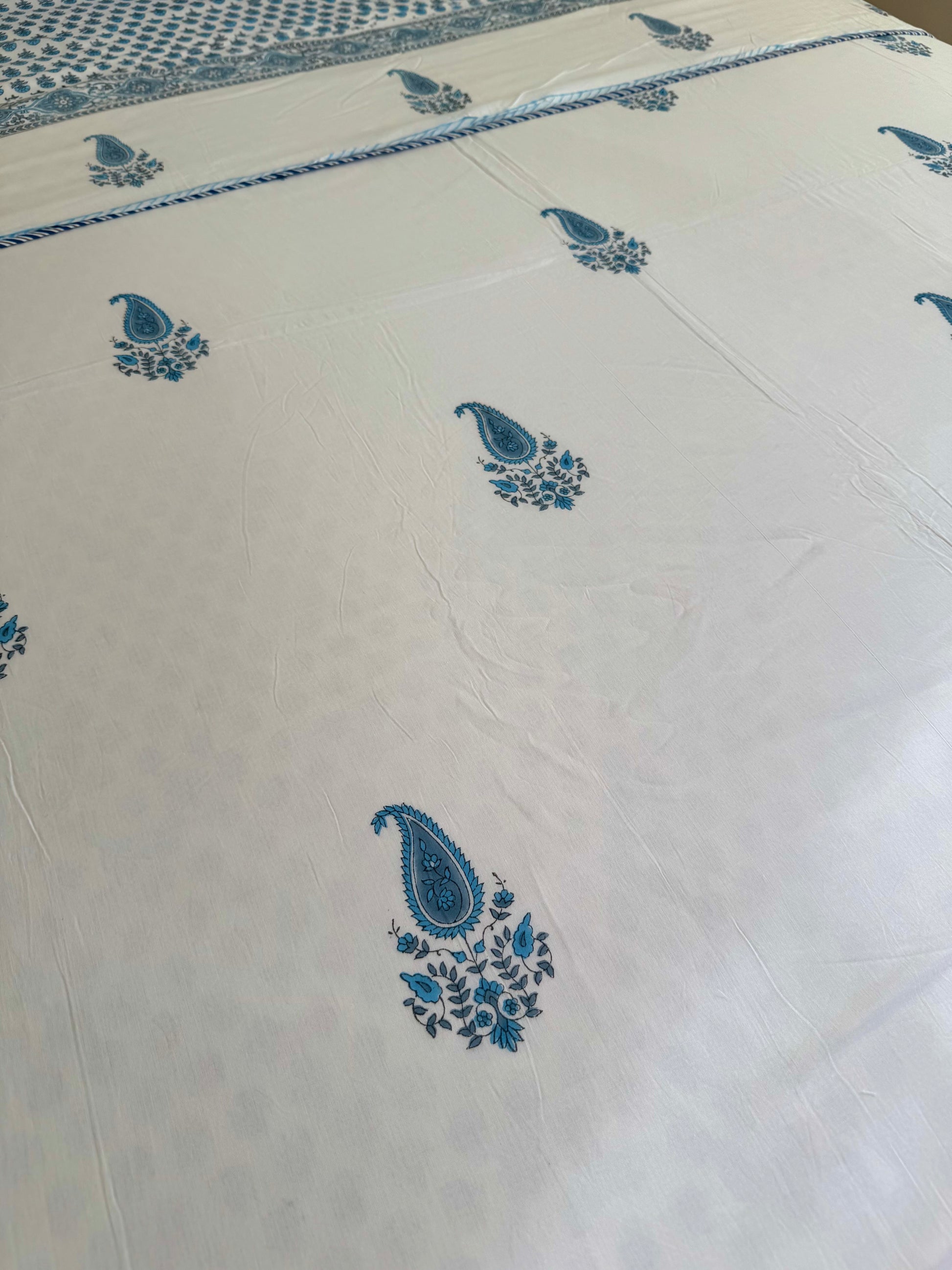 House of Mulmul - Coverlet Dohar blanket. Bedroom with reversible cotton coverlet blanket. Muslin dohar with boota paisley leaf and blue and grey colors, white background.