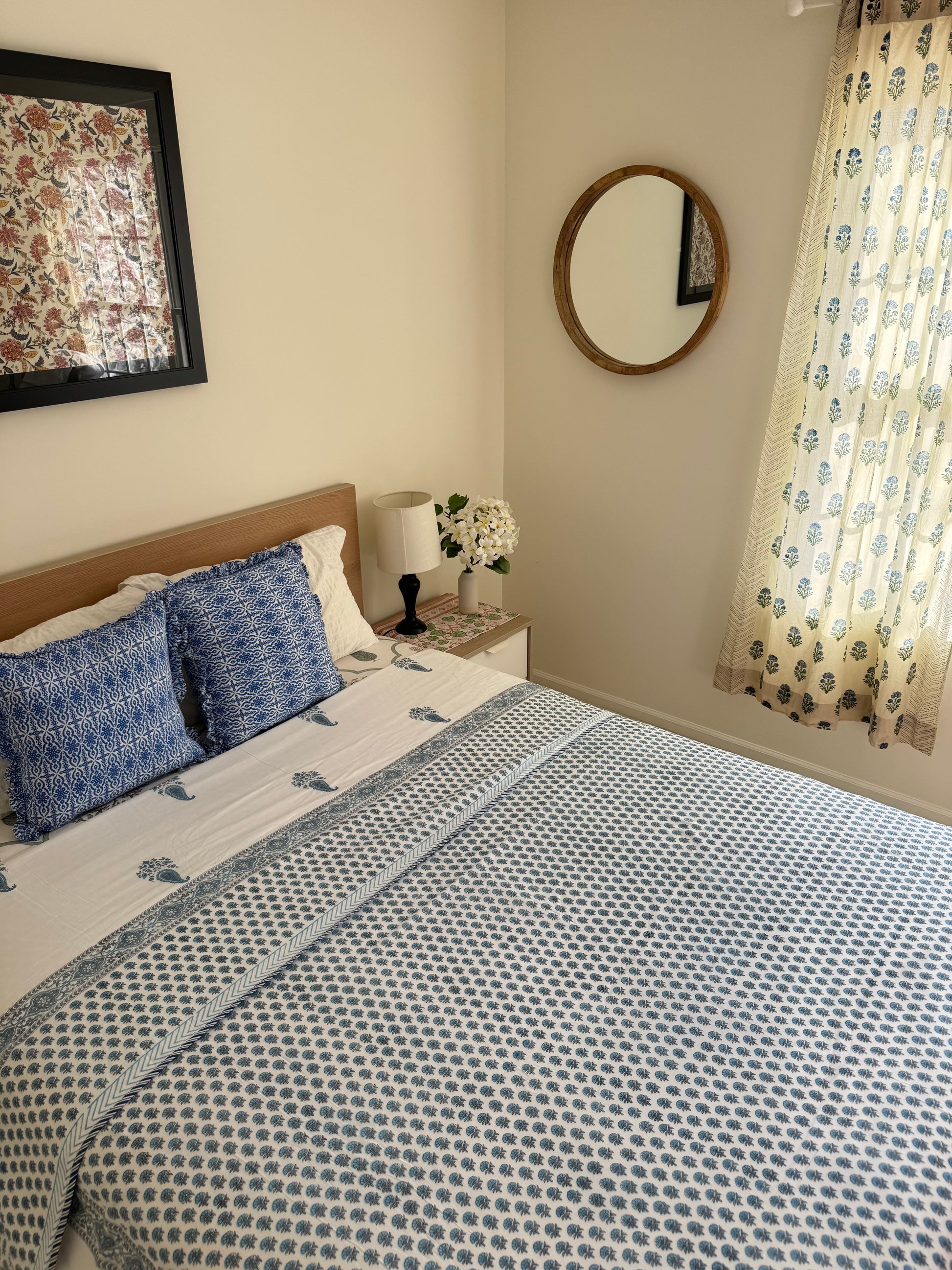House of Mulmul - Coverlet Dohar blanket. Bedroom with reversible cotton coverlet blanket. Muslin dohar with boota paisley leaf and blue and grey colors, white background. Bedroom with floral curtains, mirror.