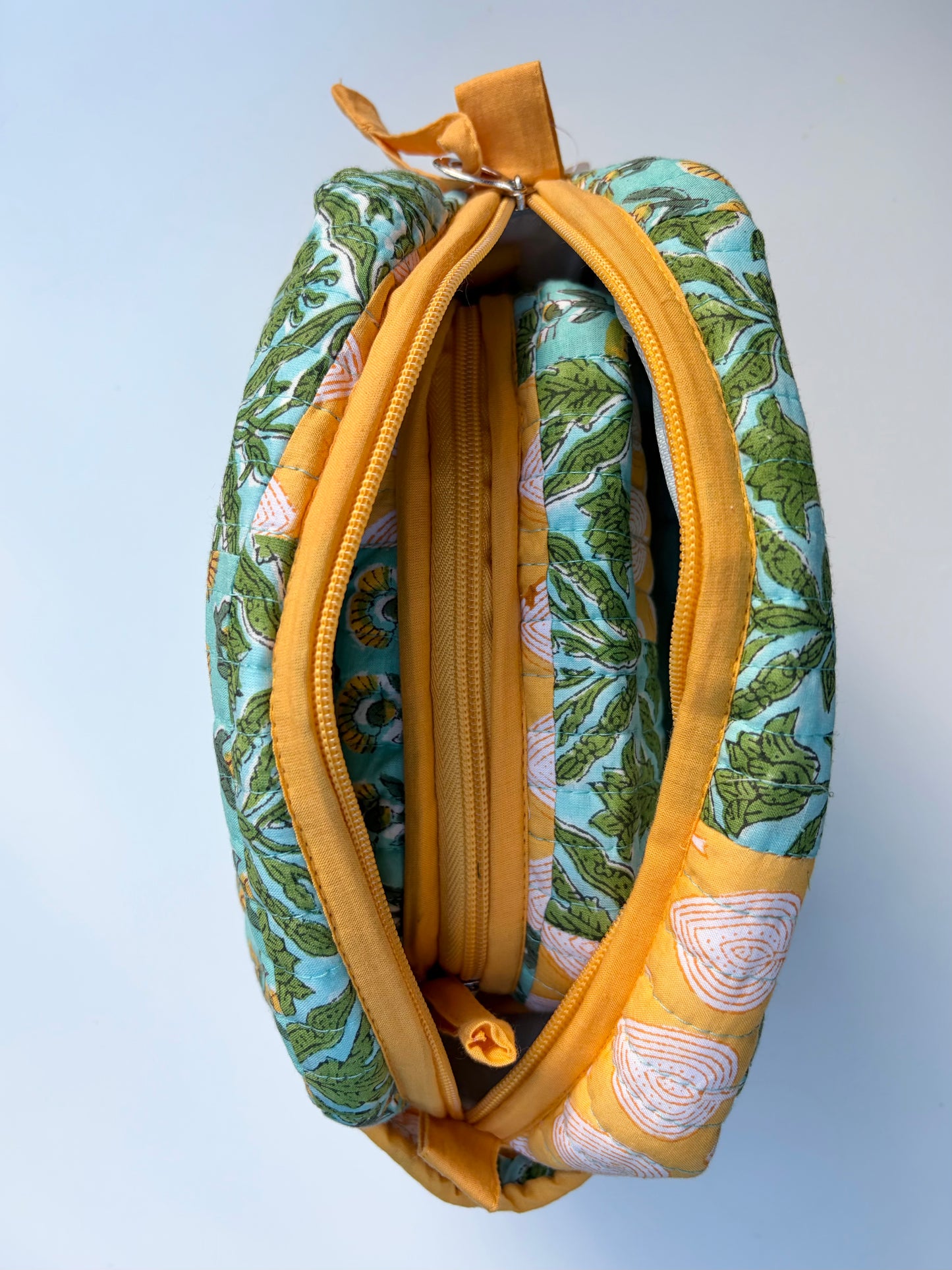 House of Mulmul - Handblock Printed Travel Makeup Quilted Pouch set. Fabric pouch with green leaf pattern and yellow zipper on a light blue background