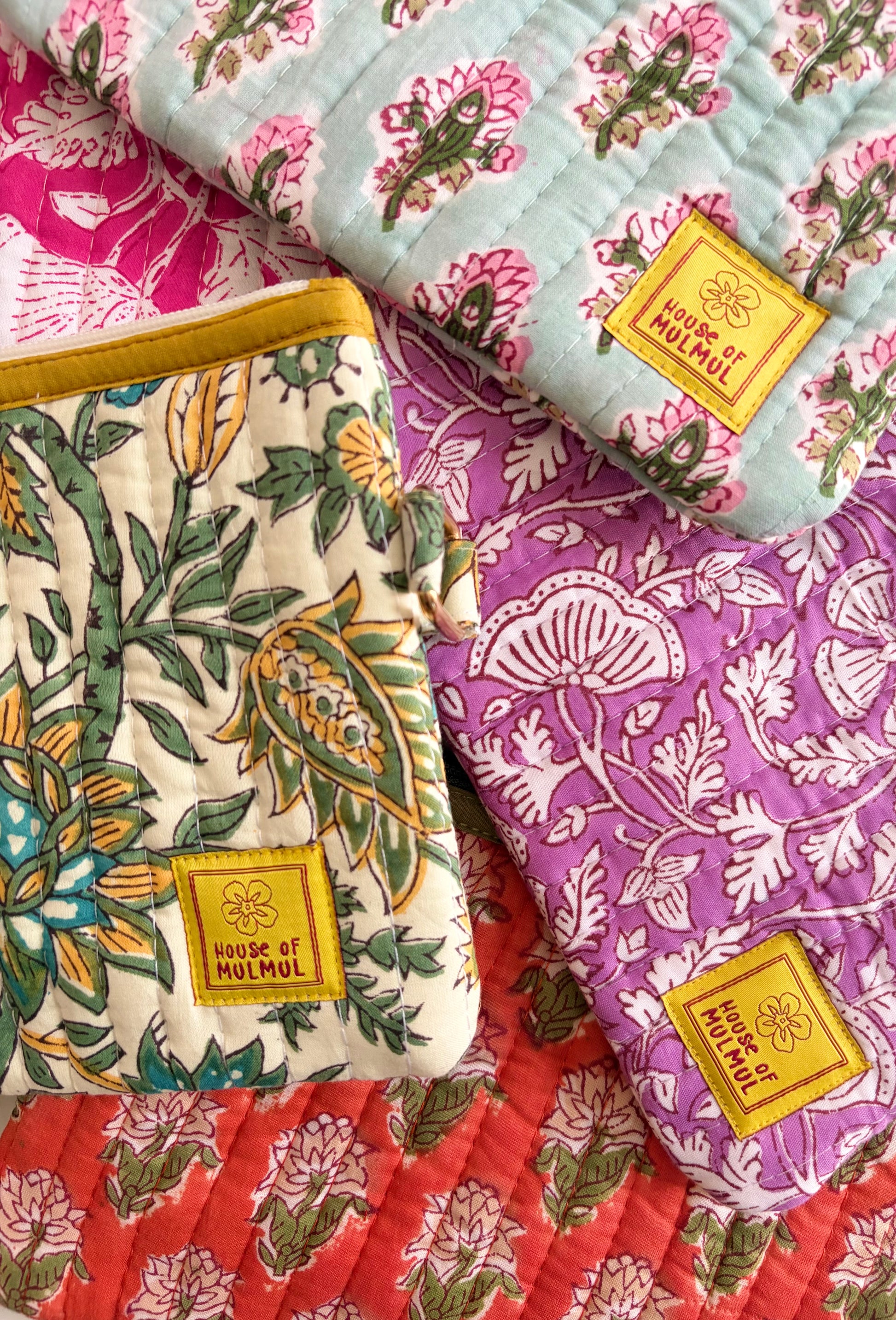 Hand Block Printed Quilted Travel Wristlet Pouch & Organizer. Fabric samples with floral patterns and 'House of Mulmul' label on a colorful background