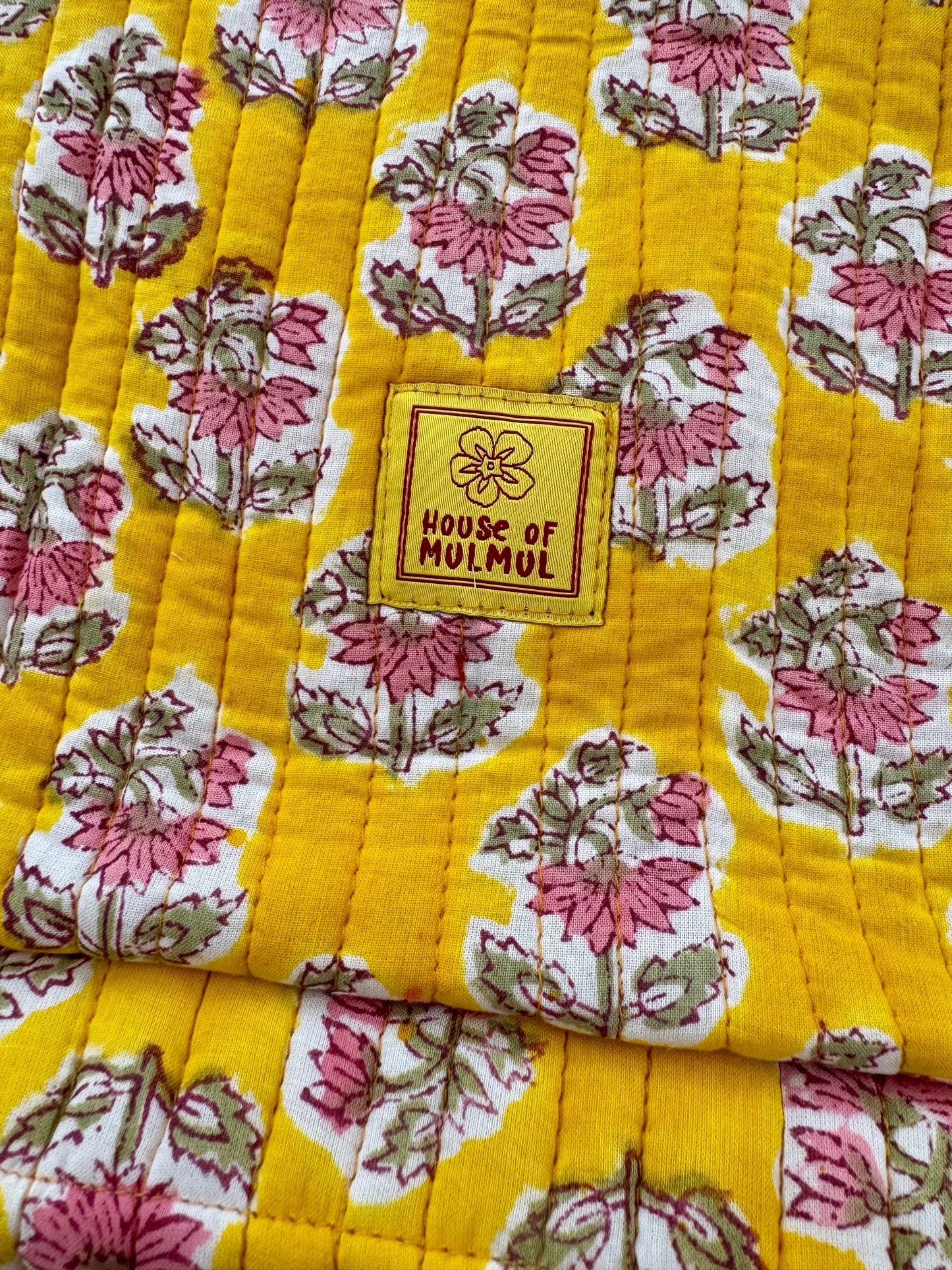 Floral patterned fabric with a 'House of Mulmul' label on a yellow background