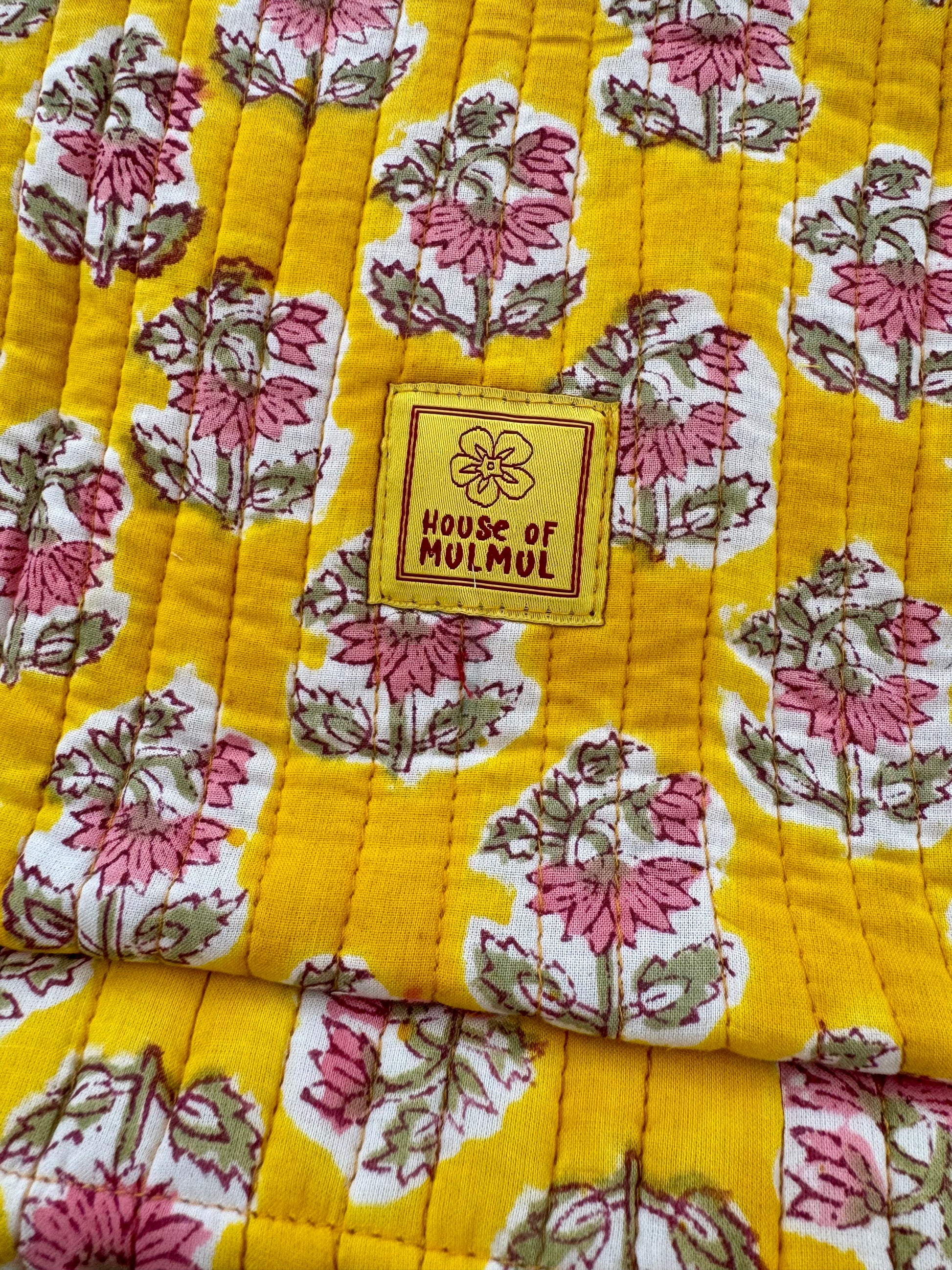 Floral patterned fabric with a 'House of Mulmul' label on a yellow background