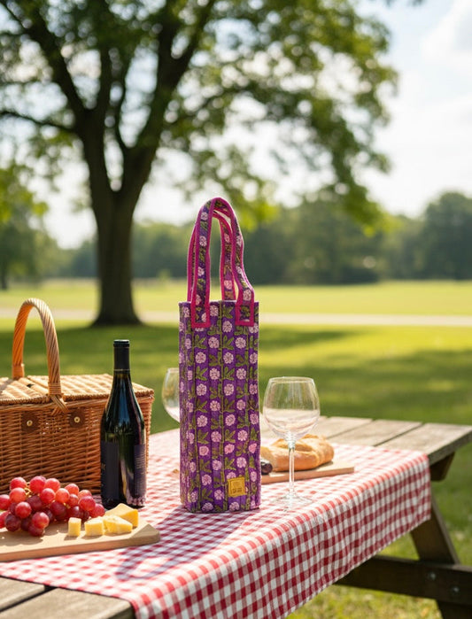 House of Mulmul - Quilted Wine Tote Bag. Picnic setup with a wine bag, bottle of wine, grapes, and bread on a checkered tablecloth in a park.