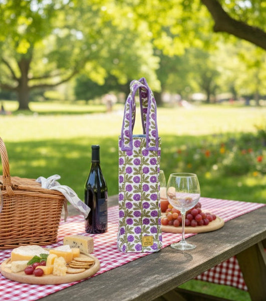 House of Mulmul - Quilted Wine Tote Bag. Picnic setup with a wine bag, wine bottle, cheese platter, and grapes on a checkered tablecloth in a park.