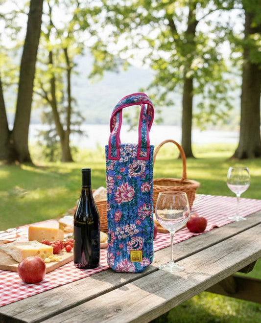 House of Mulmul - Quilted Wine Tote Bag. Floral wine bottle bag on a picnic table with wine, cheese, and fruit outdoors.