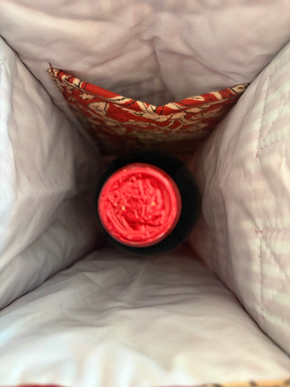 House of Mulmul - Quilted Wine Tote Bags. A close-up view from inside a white quilted insulated bag, showing a bottle with a bright pink cap resting in a patterned red and beige pocket.