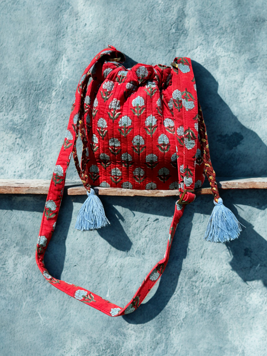 House of Mulmul - Garden Wayfarer Bucket Bag, Cotton bag, Crossbody sling bag. Red patterned bag with tassels on a gray surface