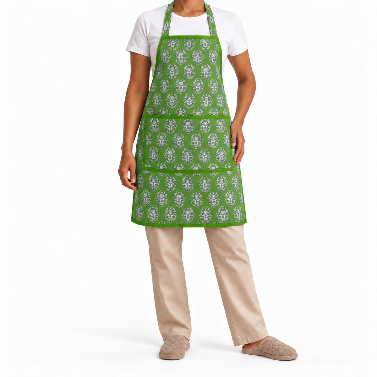 House of Mulmul - Blockprint Cotton Apron. A person wearing a bright green apron with a repeating white floral pattern, styled over a white t-shirt and beige pants on a plain white studio background.