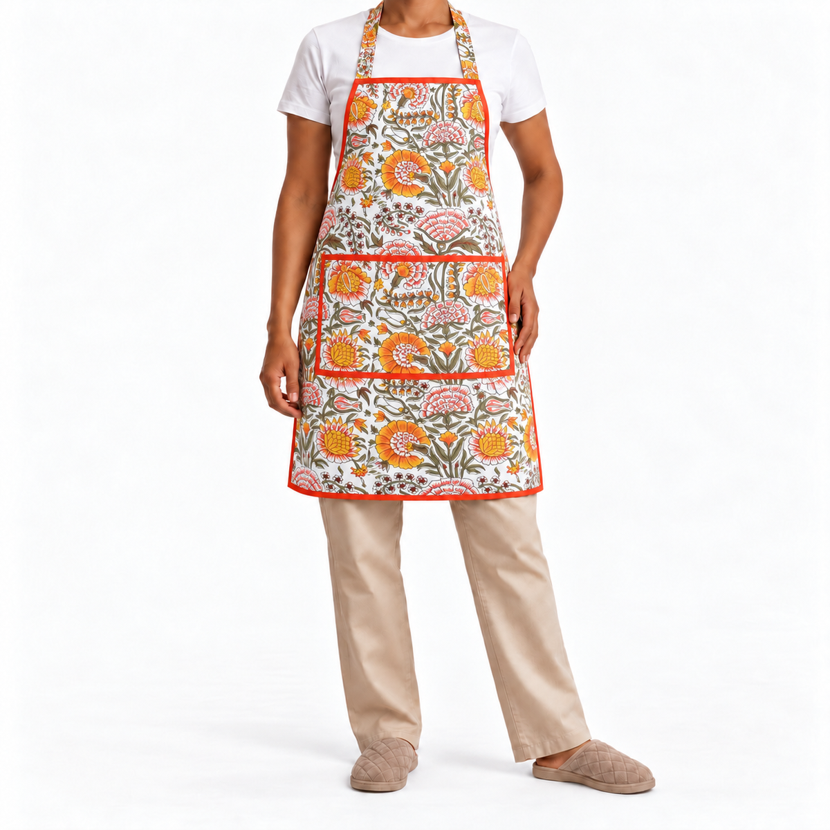 House of Mulmul - Blockprint Cotton Apron. A person wearing a white apron with a colorful floral print, styled over a white t-shirt and beige trousers, against a plain white background.